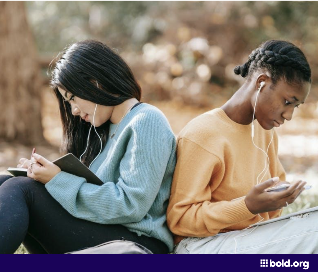 Two female students studying outside on the lawn
