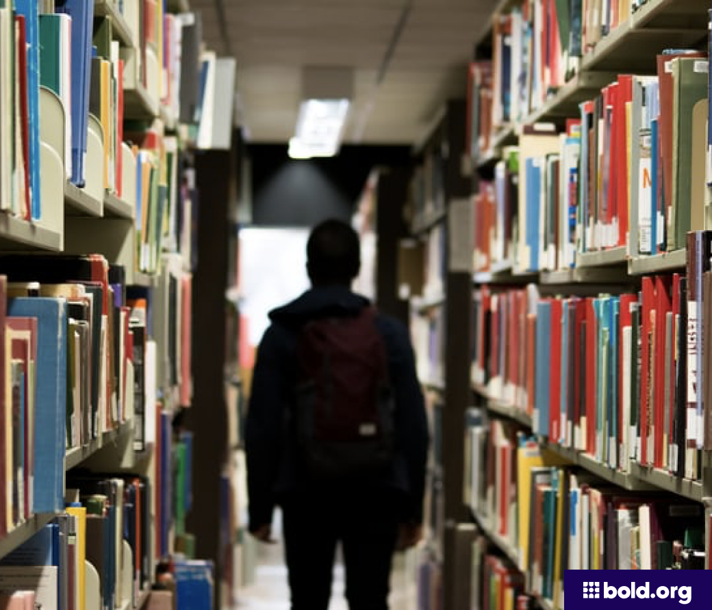 Male student with a backpack walking in a library