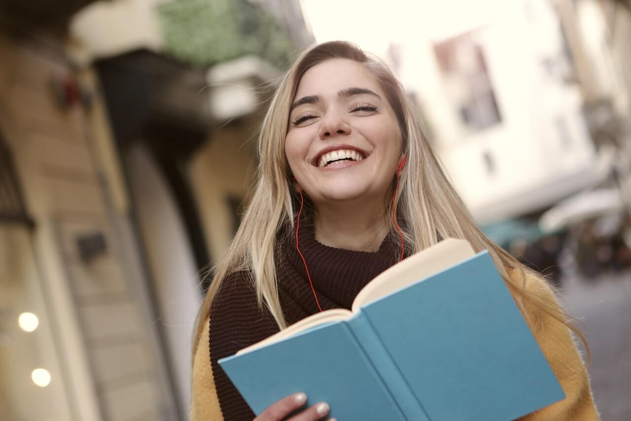 student smiling while reading a book