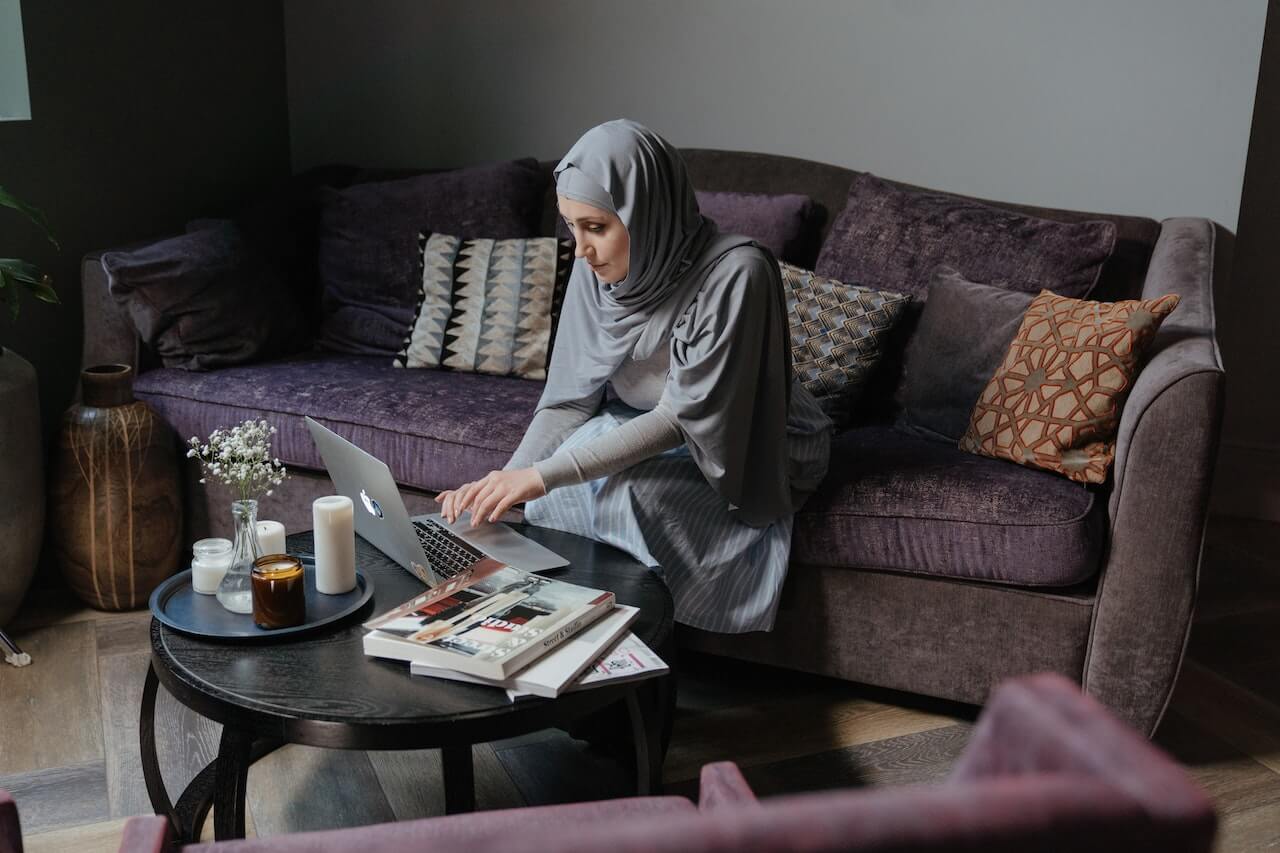 woman in hijab typing on laptop