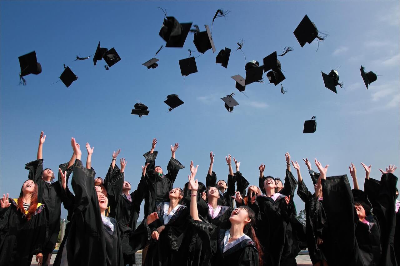 students in graduating class throwing graduation caps into the air