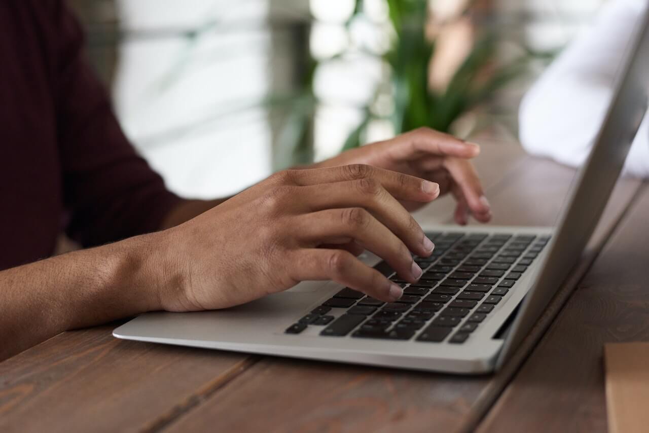 man typing on laptop searching for scholarships