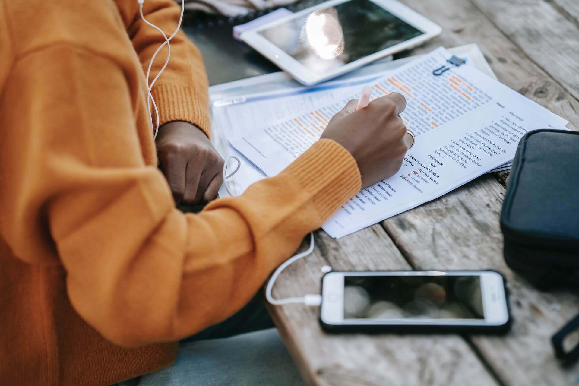 A student highlights a printed text at a table, with study supplies nearby.