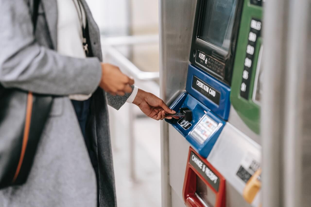 faceless woman inserting credit card into ATM