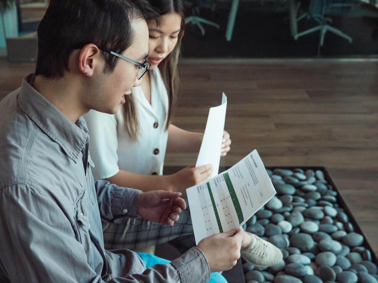 Two people converse and share paper documents.