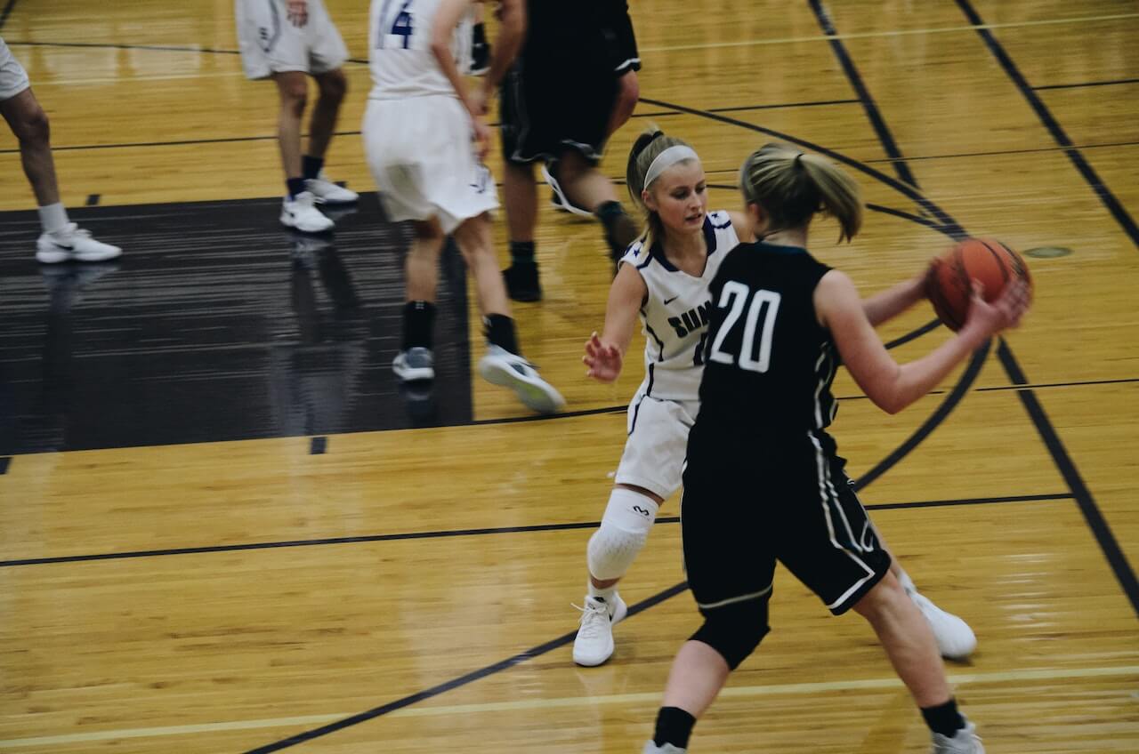 a female basketball player blocking another player on court