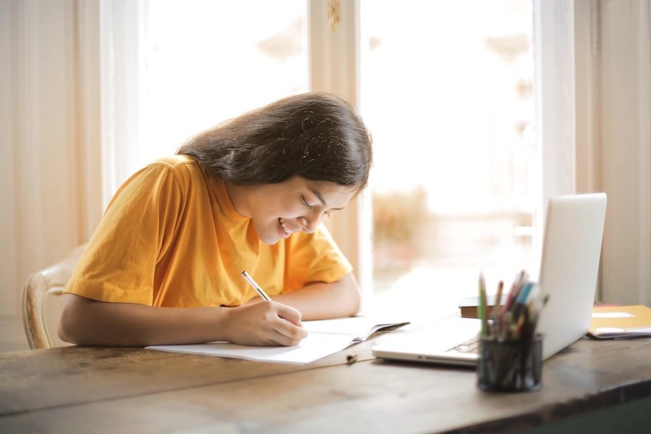 Girl in a yellow shirt studying at a table.