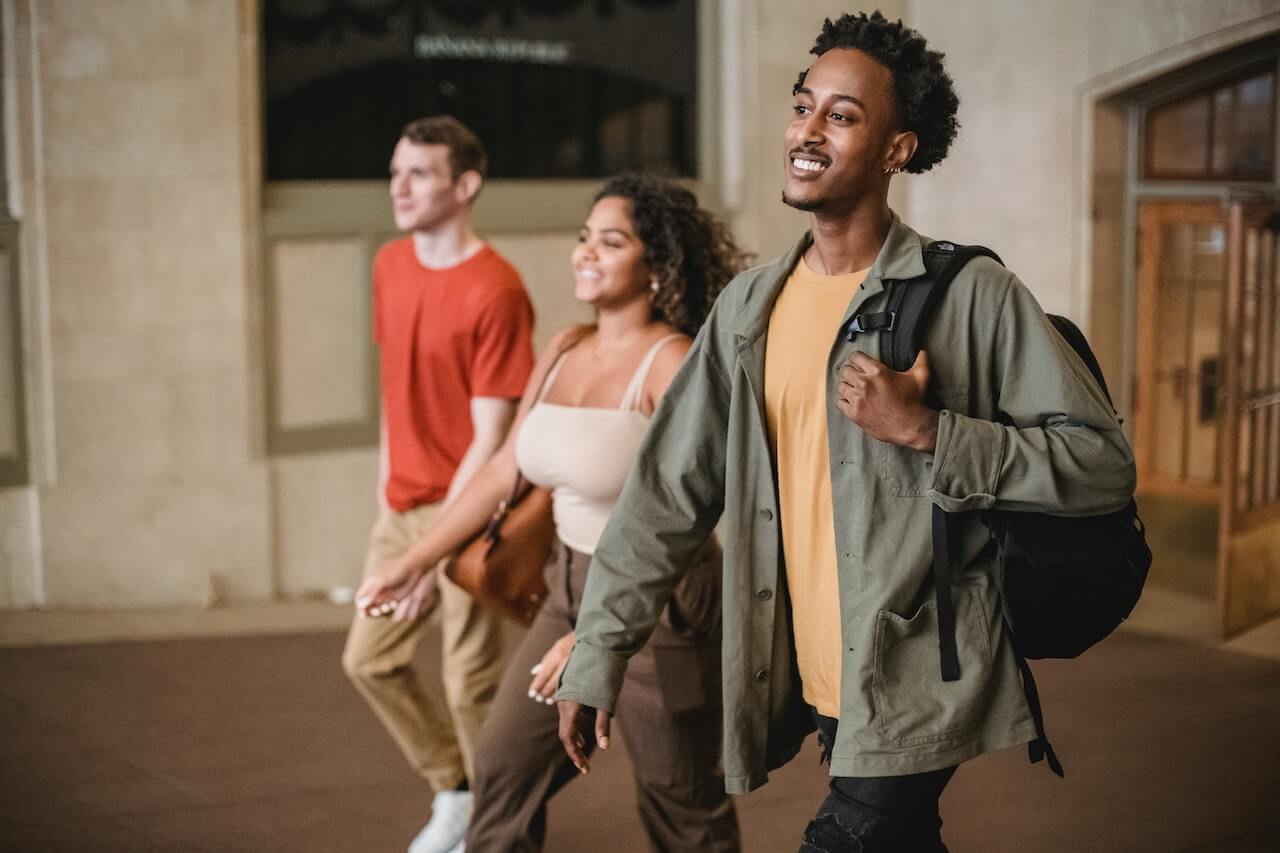 Three smiling students walking through hall