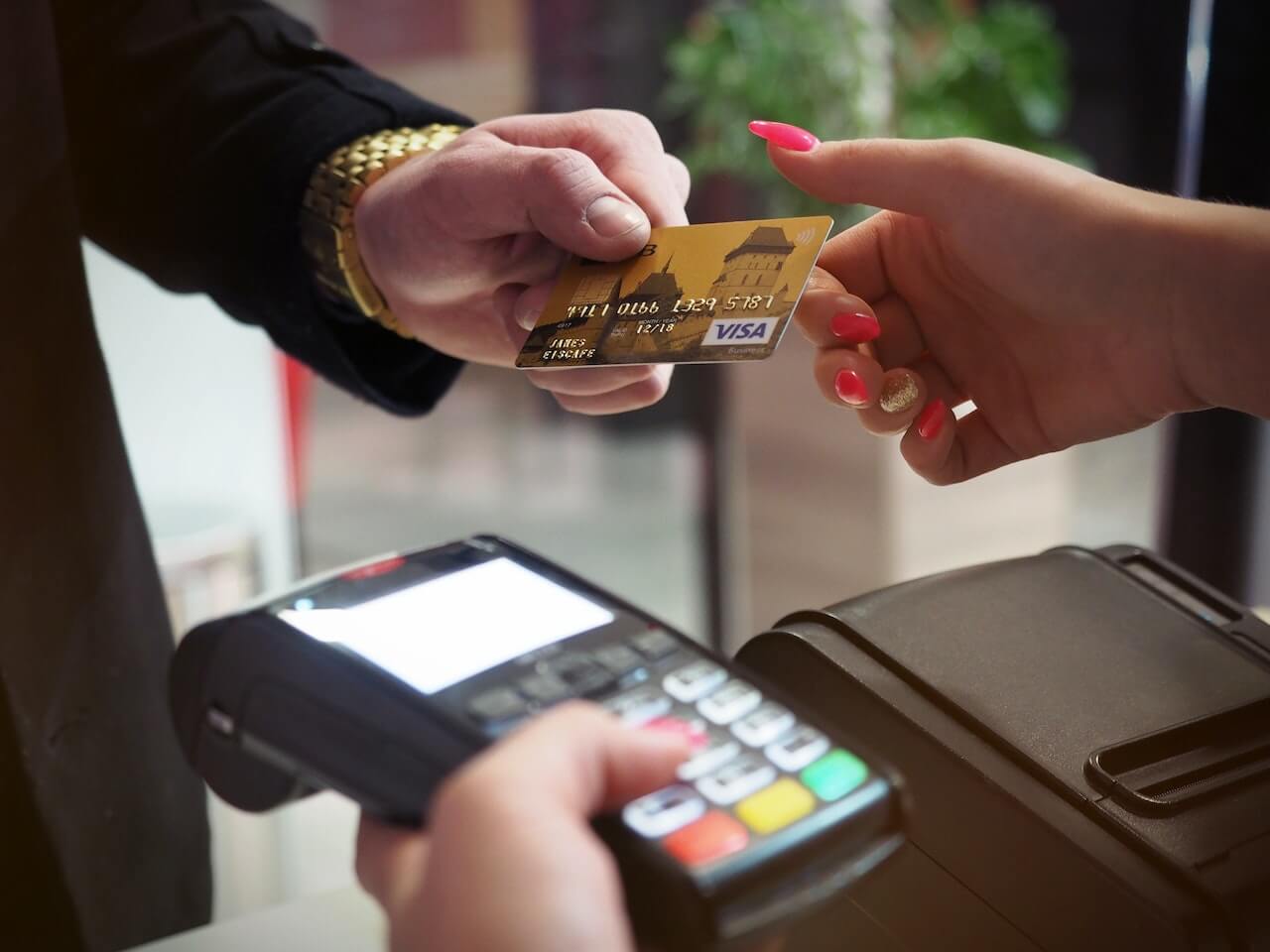 faceless man handing credit card to woman to pay