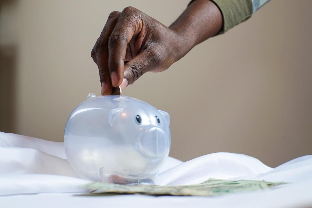 A person places a coin into a piggy bank.