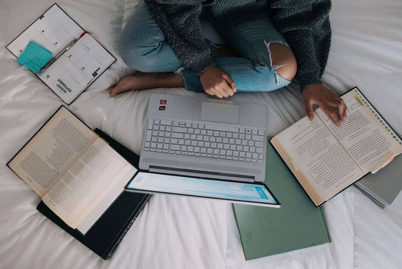 student studies laptop, books, and notebooks