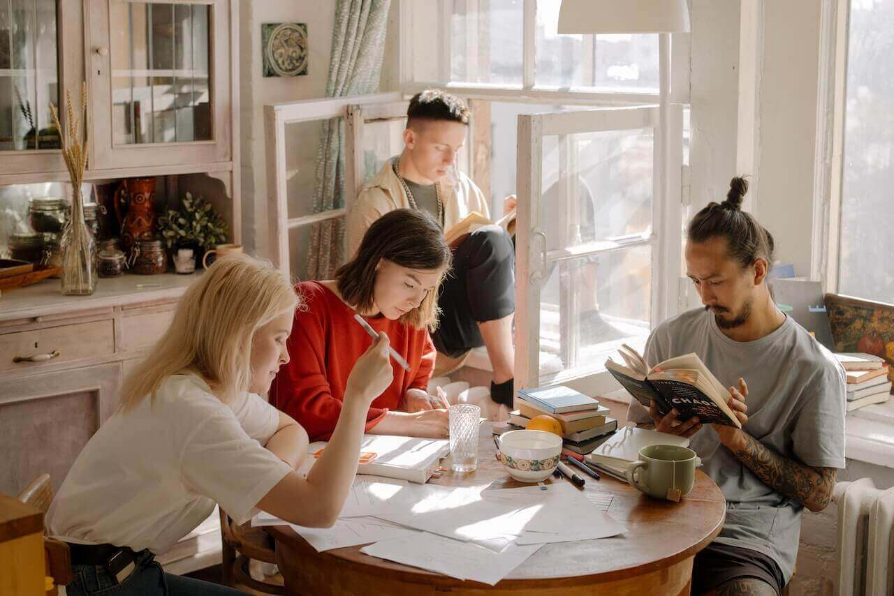 Young adults study and read together around a table.