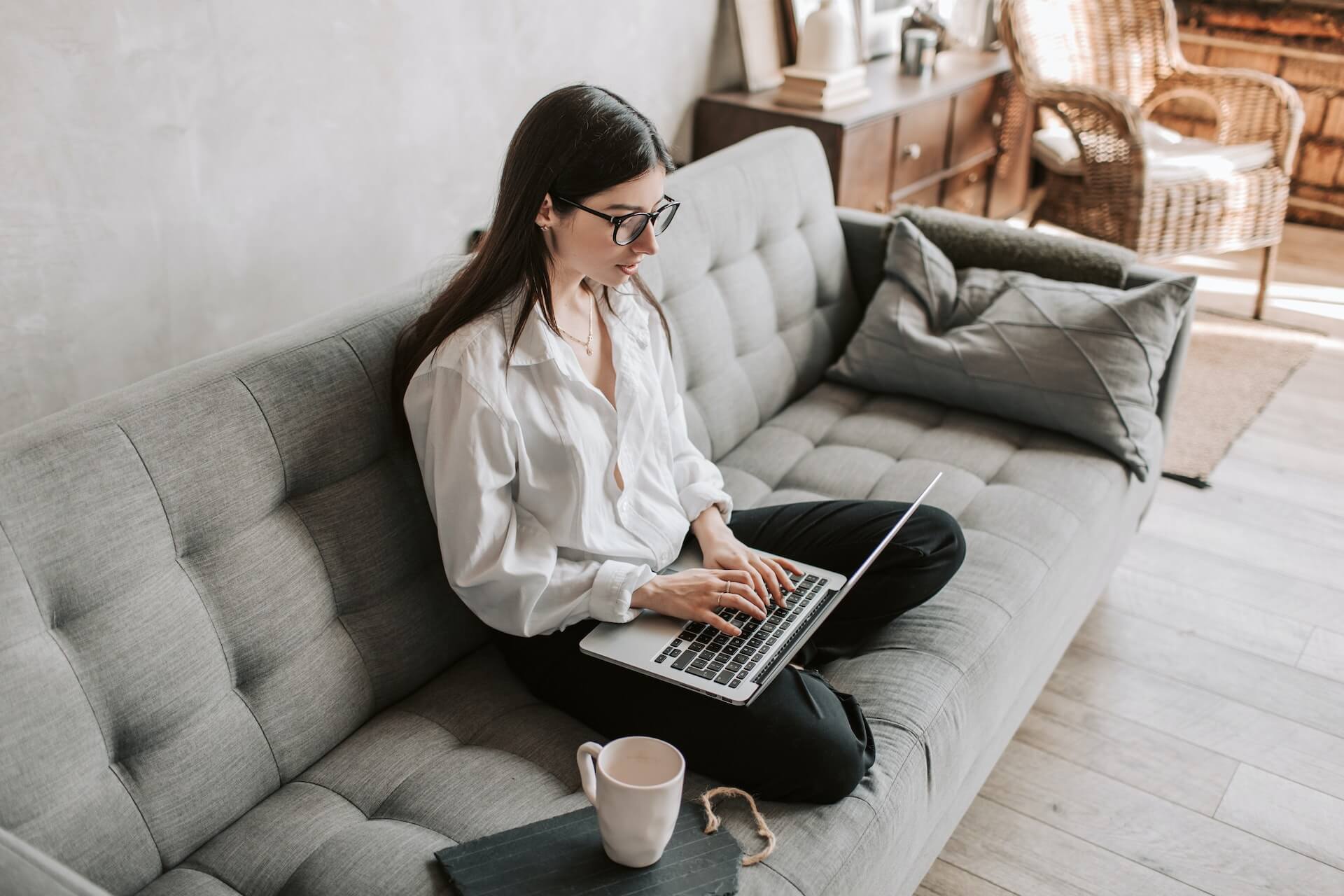 Woman working on her laptop while sitting on a couch