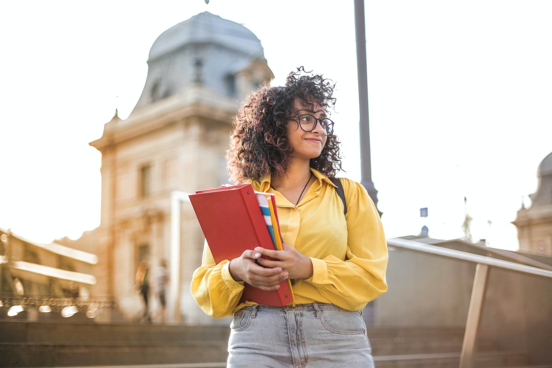 Student holding books and standing on her campus steps