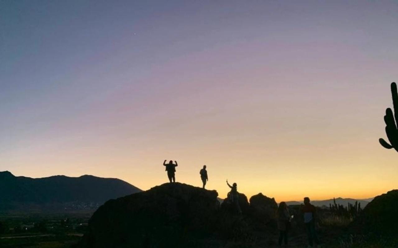 students climbing rocks at sunset