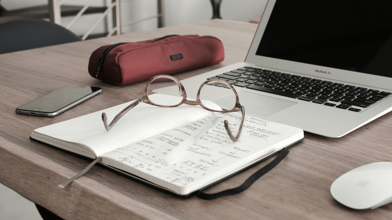 glasses on top of notebook with laptop