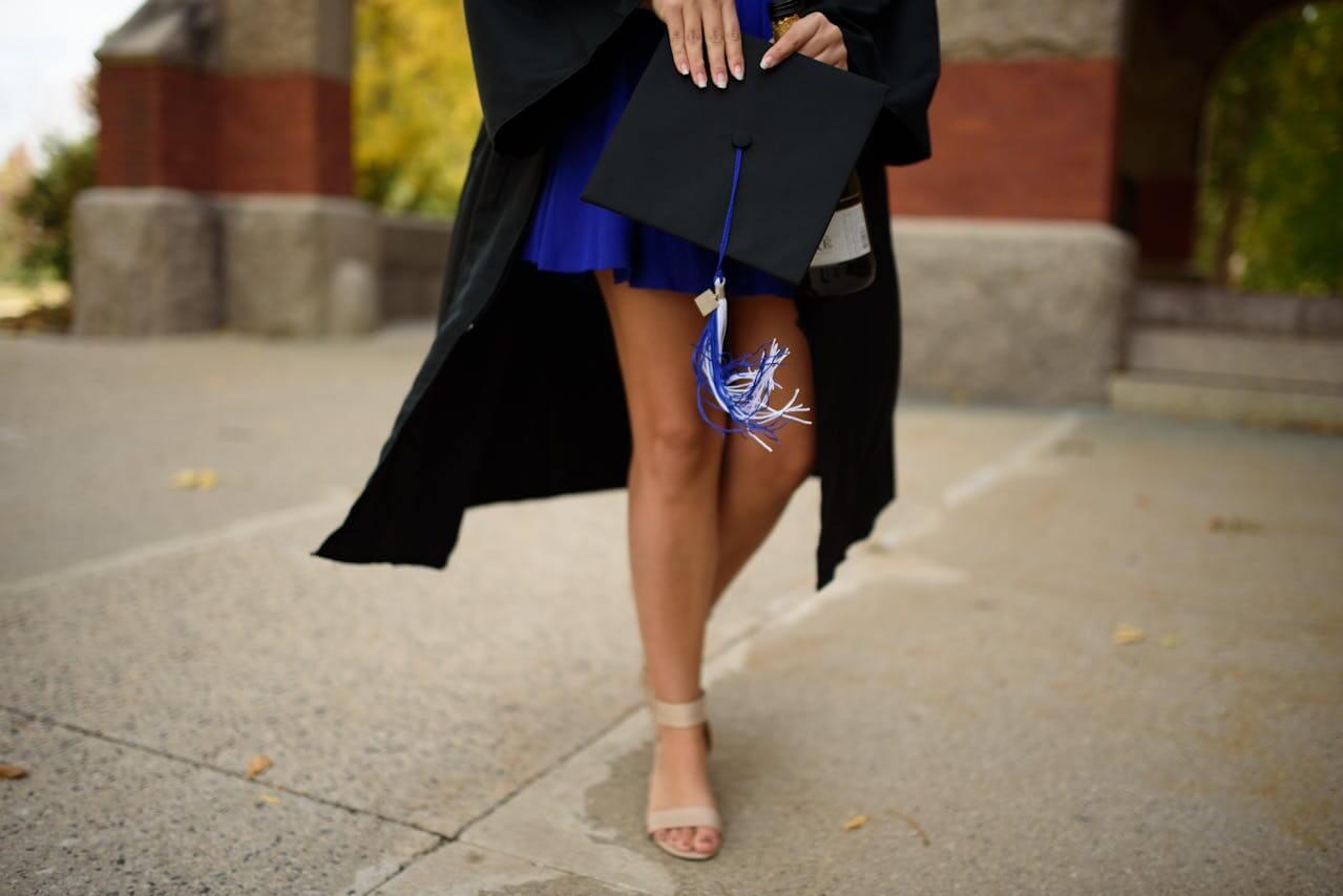 graduating student walks with cap in hand