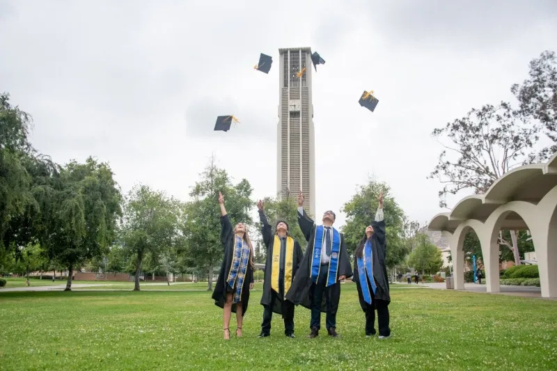 students graduating and tossing caps up in field