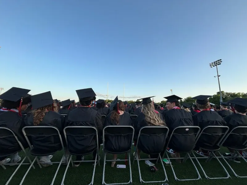 graduates sit in chairs on lawn for the ceremony