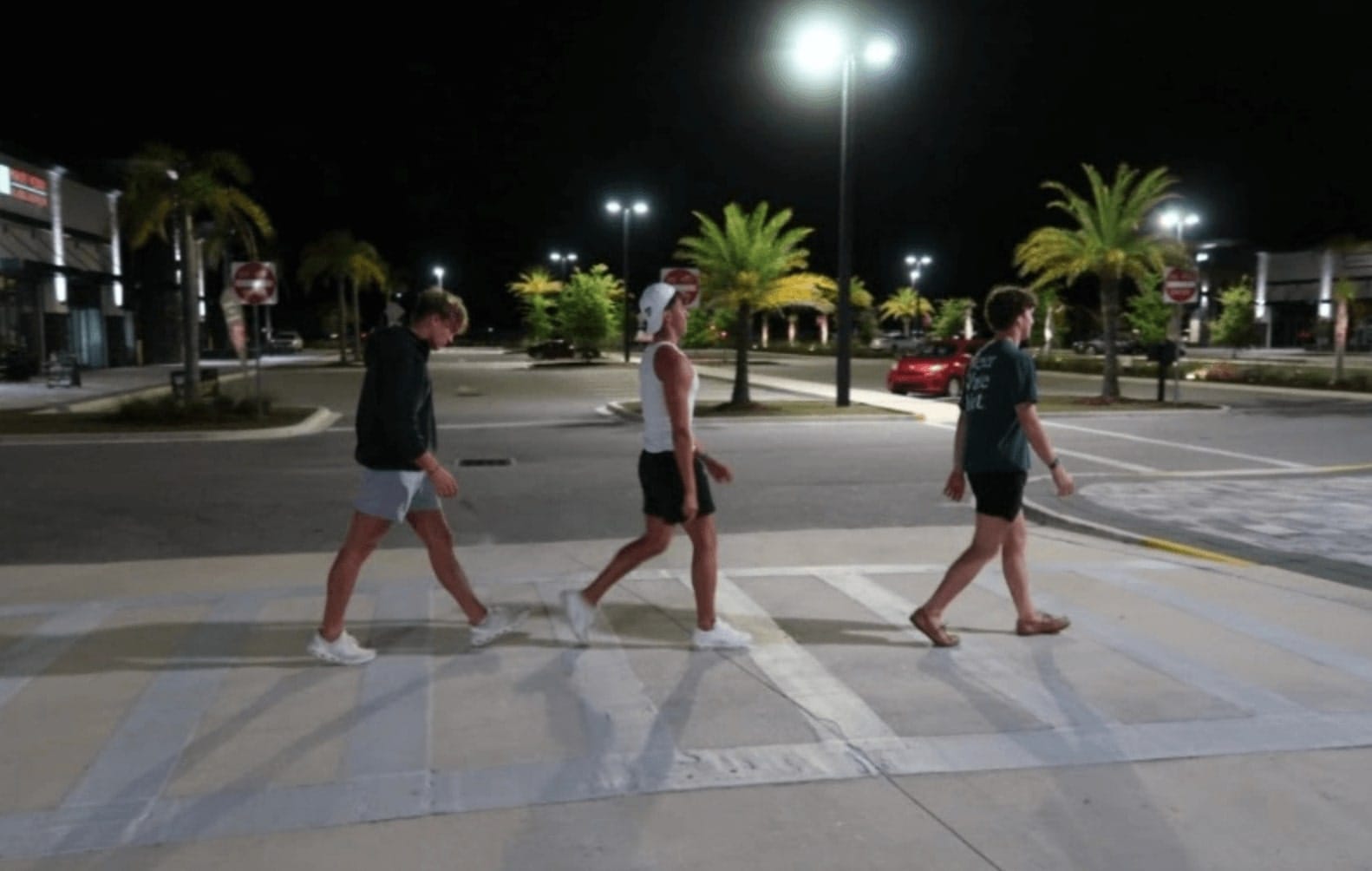 three male college students cross street at night