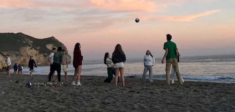 students play volleyball on a beach for spring break