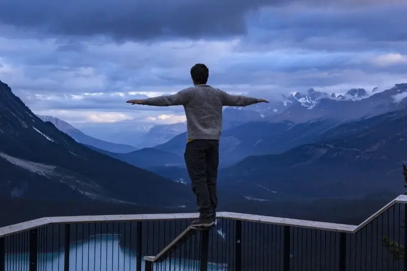 student stands on railing overlooking cinnematic mountains in minnesota