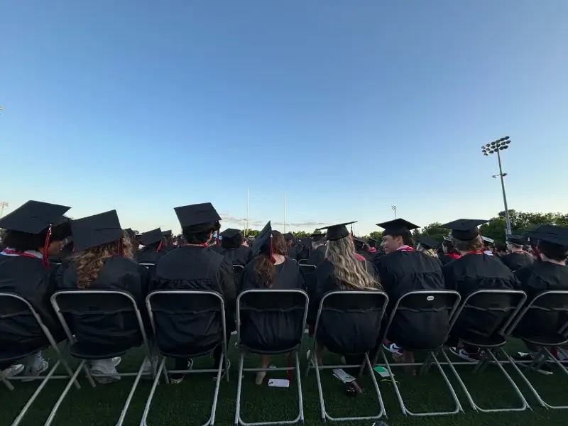 students sit in chairs for outdoor graduation ceremony