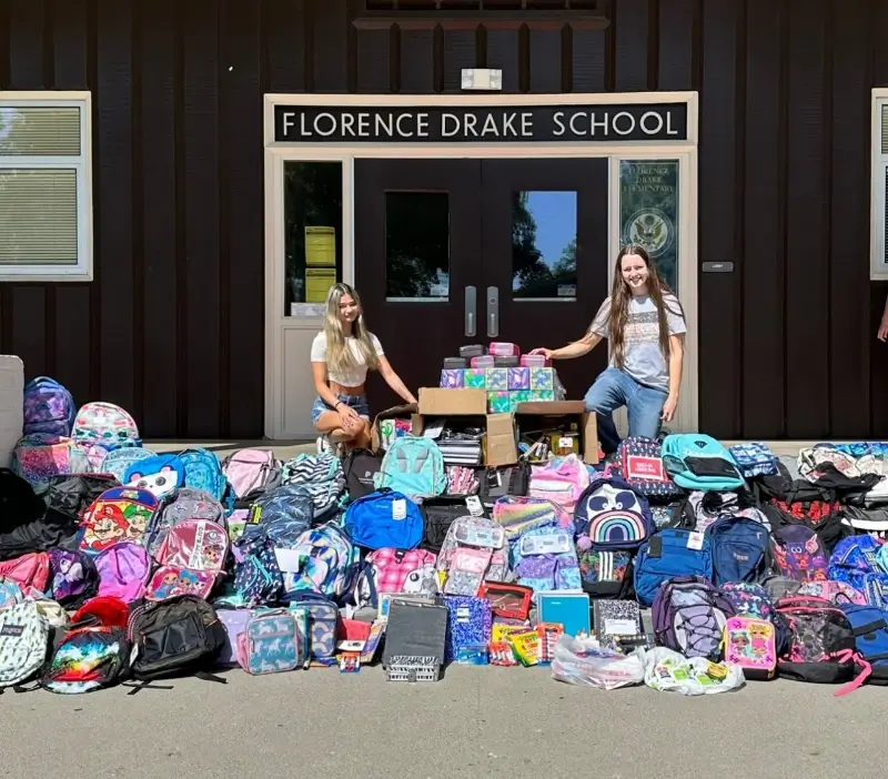 volunteers collect backpacks outside a high school