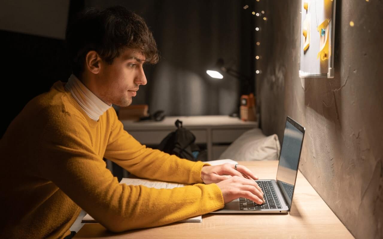 man in yellow turtleneck logs onto computer