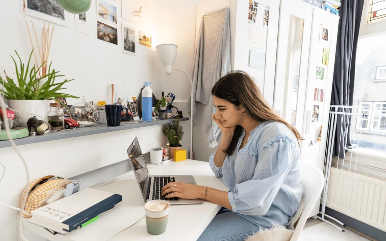 student with coffee and laptop sits at desk