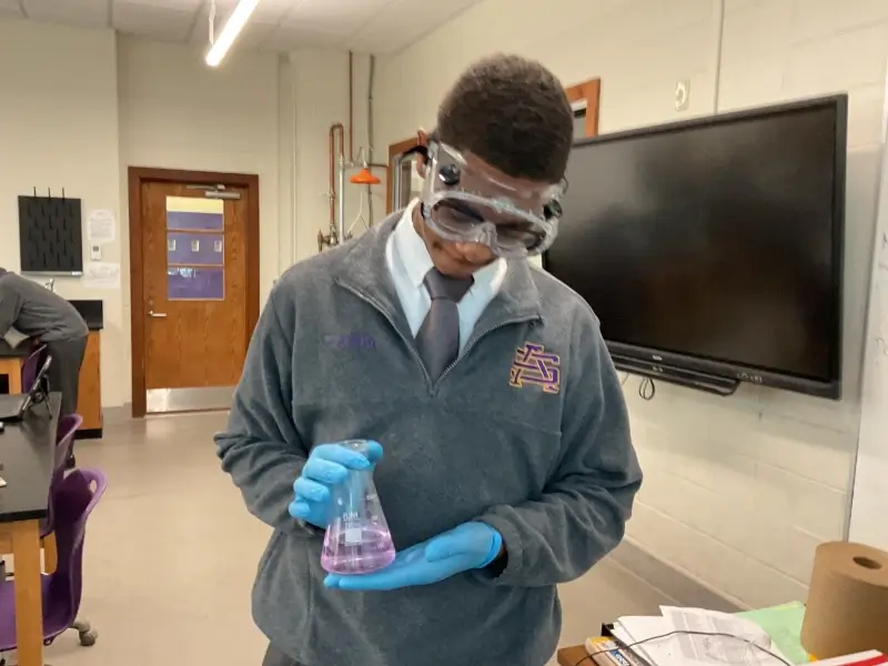 medical student in goggles examines fluid in beaker