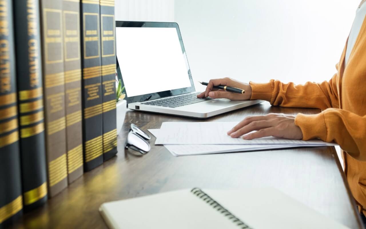 law student sits at desk with legal books and laptop