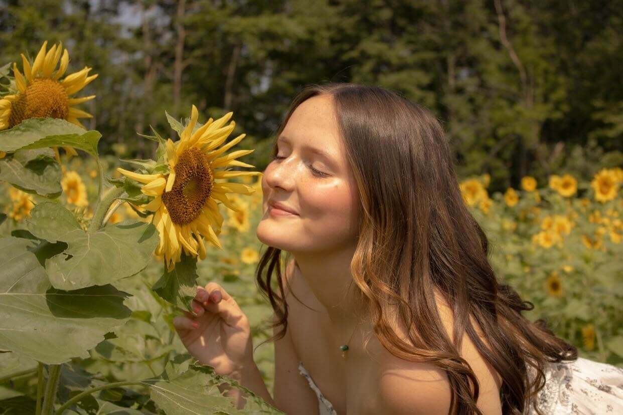 student smells sunflowers in the spring